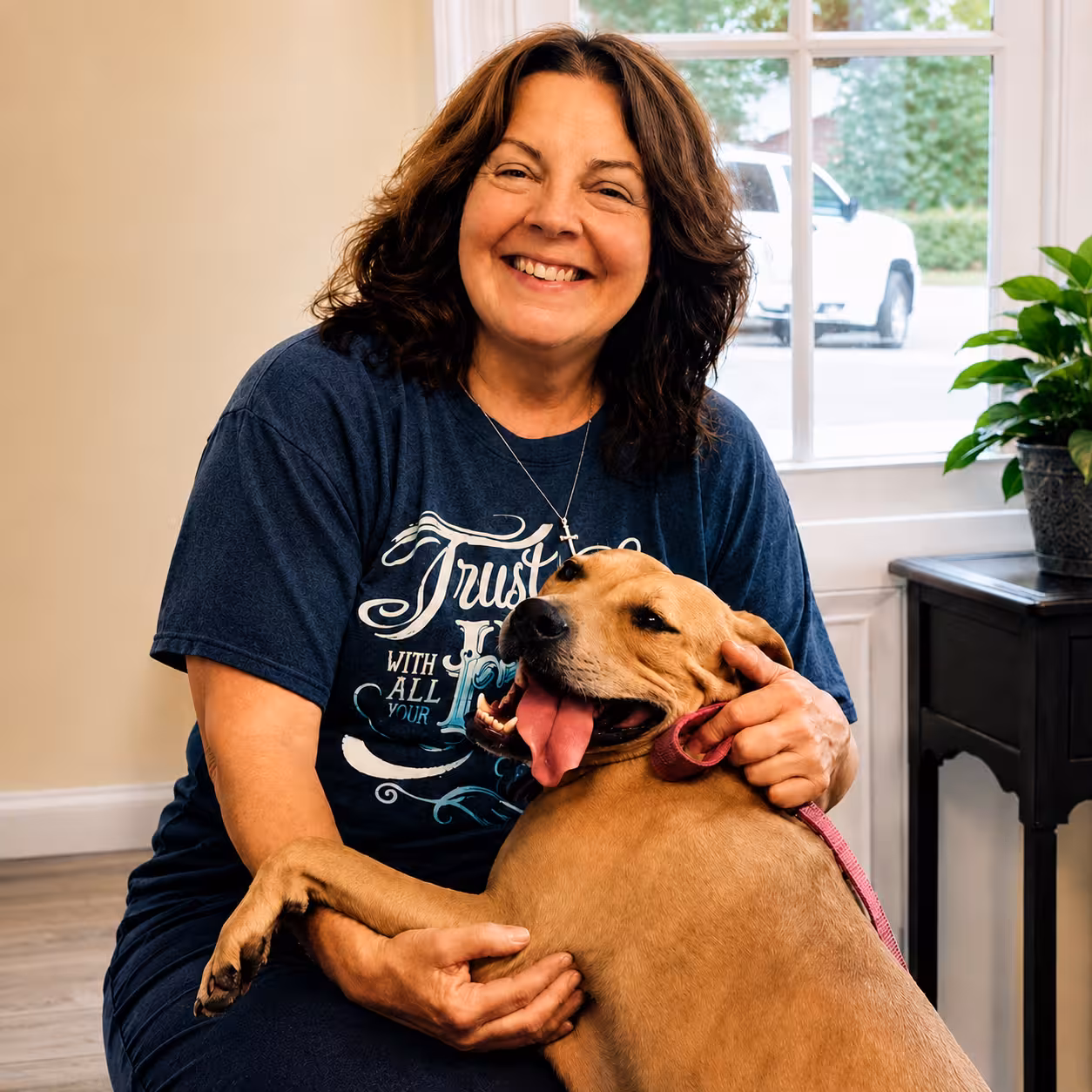 A happy woman smiling with her tan dog